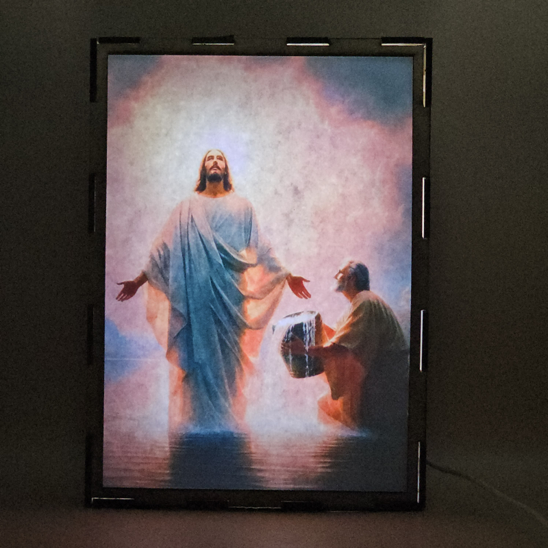 Lámpara con doble imagen el Primer misterio luminoso El Bautismo de Jesús en el Jordán (Nuestro Señor Jesucristo, San Juan Bautista), vista encendida, con luz ambiente, donde se revela la ilustración completa al encender la luz LED.