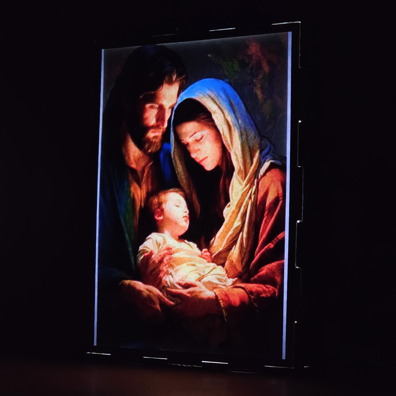 Lámpara con doble imagen  (San José, La Virgen María, El niño Jesús), vista encendida, donde se revela la ilustración completa al encender la luz LED.