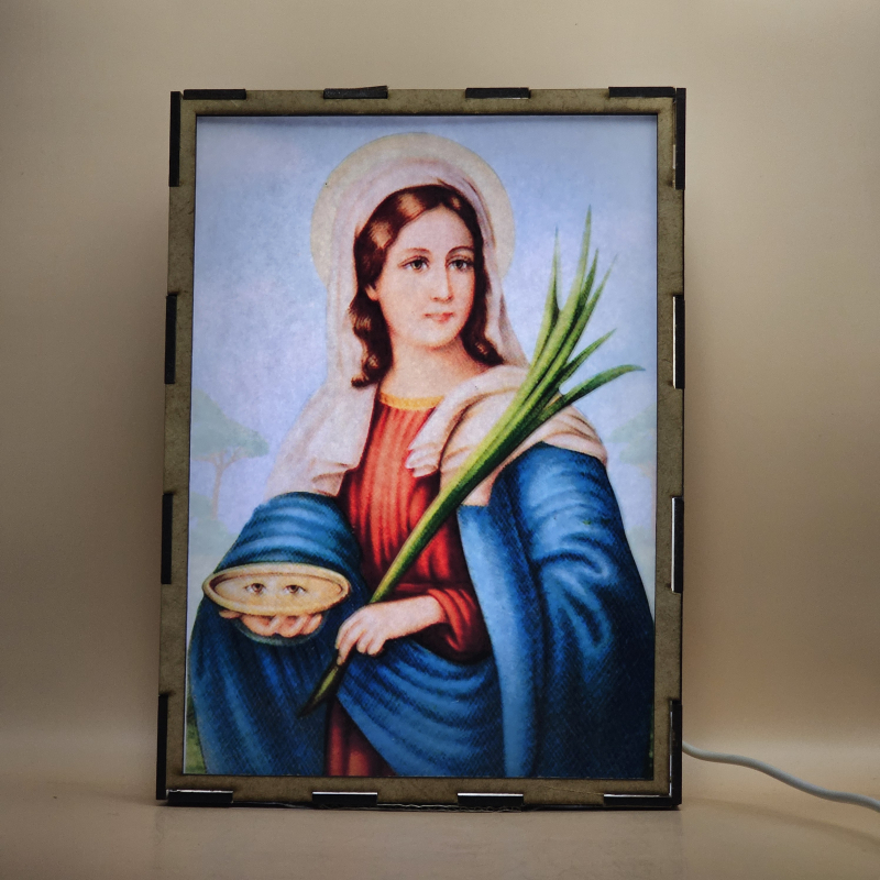 Lámpara con doble imagen  (Santa Lucía), vista encendida, con luz ambiente, donde se revela la ilustración completa al encender la luz LED.