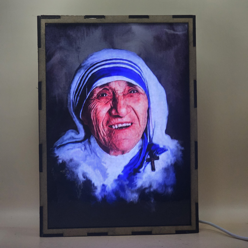 Lámpara con doble imagen  (Santa Teresa de Calcuta), vista encendida, con luz ambiente, donde se revela la ilustración completa al encender la luz LED.